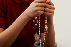 a student's hands holding a rosary