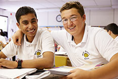 two smiling students, one with his arm around the other