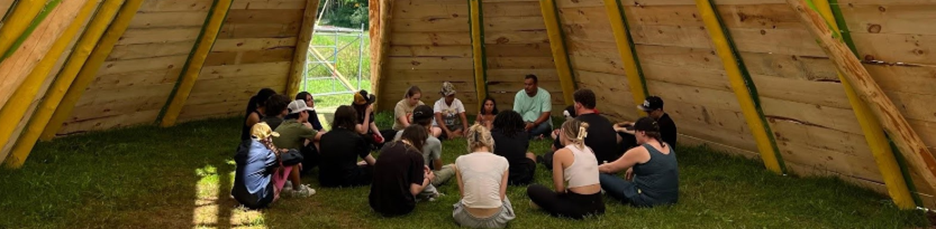 Image of people sitting in a circle in a Tipi